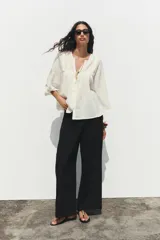 Blusa color crema de cuello redondo con escote pico y manga ancha por debajo del codo. Detalle de acabados con bordados. Cierre frontal con botones.
