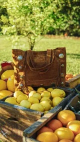 Cartera marrón de cuero y gamuza con textura croco, estilo boho, con doble asa corta y flecos.