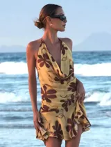 Vestido corto con estampado floral en tonos amarillos y marrones, con escote halter y espalda descubierta.