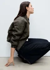 Chaqueta acolchada color verde militar con cuello perkins, cierre frontal con botones, dos bolsillos laterales y detalle fruncido en el bajo. Estilo bomber.