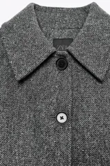 Abrigo corto gris jaspeado con cuello solapa y manga larga. Cierre frontal con botones.