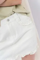Minifalda de denim color crema con volados en los bolsillos delanteros y en el ruedo.