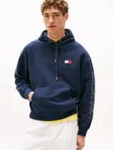 Buzo azul marino amplio con capucha y cordón distintivo, bolsillo canguro, puños y bajo de punto canalé, logo oversize de Tommy Hilfiger en la manga y la parte trasera, parche con logo de Tommy Hilfiger en el pecho y detalles distintivos de Hilfiger Sailing.