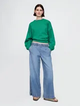 Pantalón de jean celeste, corte ancho, con cintura elástica y bolsillos laterales.