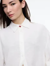 Camisa celeste de calce relajado con abertura en la espalda y mangas largas. Confeccionada en tejido liviano de lino y viscosa. Incluye tres pins decorativos.