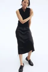 Pollera midi negra con leve brillo y caída suave. Modelo de tiro alto con elástico oculto en la cintura y leve vuelo en el bajo.