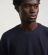 Remera azul marino de corte regular, confeccionada en tejido de piqué de algodón. Tiene cuello redondo con rib, mangas cortas y diseño liso.