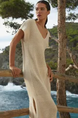 Maxi vestido tejido color beige con diseño de flecos en el bajo, ideal para el verano.