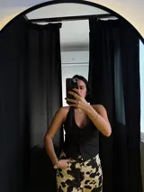 Chaleco negro con escote halter y cierre frontal con botones.