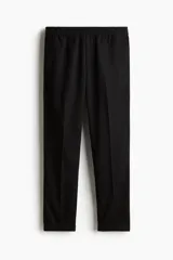 Pantalón negro de sarga con cintura elástica y cordón ajustable, corte slim fit, largo tobillero y dobladillo en el bajo.