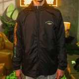 Campera negra tipo windbreaker con capucha, cierre frontal y puños elásticos. Logo de Kaboa en el pecho y estampado con el logo de Jägermeister en la manga.