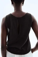 Musculosa negra en tejido de punto texturizado con escote redondo y abertura de cerradura con botón en la nuca. Sin mangas.
