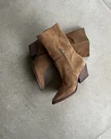 Bota corta plateada de cuero sintético, con punta fina y taco geométrico.