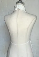 Top blanco con textura, cuello halter y abertura en el frente.