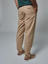 Pantalón color beige de corte regular fit, confeccionado en lino. Cuenta con dos bolsillos frontales y dos bolsillos posteriores, bajo con botamanga y presilla, aplique de badana.