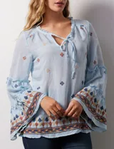 Blusa celeste de gasa bordada, con escote en V y lazo de ajuste. Mangas largas con terminación amplia.
