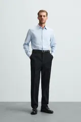 Camisa negra de manga larga con cuello italiano y cierre frontal de botonadura. Presenta un tejido con estructura de fácil cuidado.