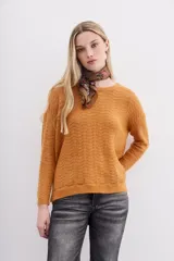 Sweater color mostaza de tejido de punto con detalle de lentejuelas integradas al hilado, calce holgado y mangas largas.