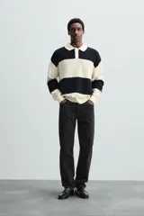 Sweater tipo polo de punto con rayas horizontales anchas en color negro y crudo, con cuello clásico y cierre de dos botones.