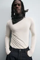 Camiseta de manga larga color crudo, corte ajustado y cuello redondo. Tiene aberturas en los puños y efecto lavado.