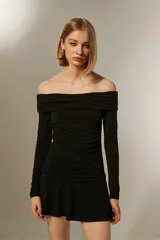 Vestido negro corto con escote off-shoulder, mangas largas y falda con volados. Diseño ajustado al cuerpo.
