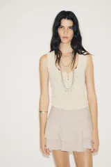 Falda pantalón color crema, de tiro medio, con volantes en capas y cierre lateral con cremallera.