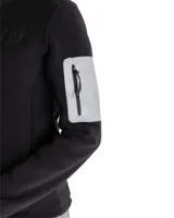 Buzo polar negro de poliéster con cierre frontal completo, cuello alto, bolsillos laterales y bolsillo reflectante con cierre en la manga izquierda.