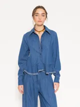 Camisa de denim liviano color azul, con ruedo curvo, canesú en forma de V en la espalda y acceso mediante botones.