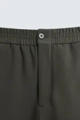 Pantalón verde oscuro de corte recto, con cintura elástica, bolsillos laterales y un bolsillo trasero. Cierre frontal con cremallera y botón.