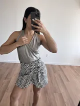 Minifalda de gabardina con estampado animal print blanco y negro, con volados en el ruedo y lazo ajustable en la cintura.