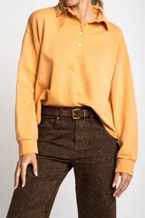 Sweater color naranja con cuello polo y botones, de corte holgado y mangas largas.