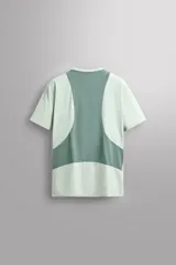 Camiseta deportiva verde claro confeccionada en tejido técnico, ligero y elástico en cuatro direcciones. Tiene cuello redondo, manga corta, zonas con estructura perforada y logo estampado.
