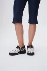 Zuecos de cuero con estampado animal print blanco y negro, con plataforma y hebillas metálicas.