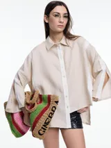 Camisa de lino color negro con silueta amplia y mangas 3/4. Diseño con tiras de color blanco en contraste en la cartera, mangas y cuerpo. Tiene tajos laterales y ruedo irregular en el frente.