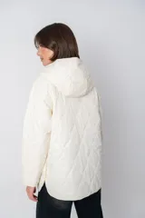 Campera color crema con diseño acolchado en forma de rombos, capucha y cierre con botones a presión.