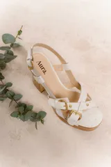 Sandalias de cuero negro con plataforma de madera y taco ancho. Presentan tiras anchas cruzadas sobre el empeine con hebillas doradas ajustables y pulsera al tobillo con hebilla.