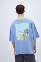 Remera celeste de algodón con calce boxy, teñida en prenda y con estampa fotográfica en la espalda.