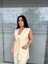 Chaleco amarillo con rayas verticales, cuello en V, cierre con un botón dorado y bolsillos delanteros.