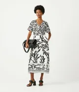 Pollera midi color blanco con estampado de hojas negras, cintura alta y corte recto.