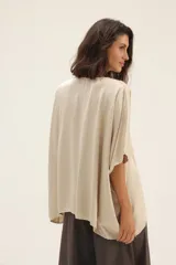 Blusa beige de seda con escote en V y mangas cortas tipo murciélago.