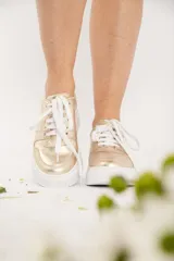 Championes dorados con cordones blancos y suela blanca con plataforma.