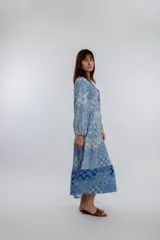 Vestido midi de corte amplio con estampado floral en tonos azules y blancos. Tiene cuello mao con botones y mangas largas abullonadas.