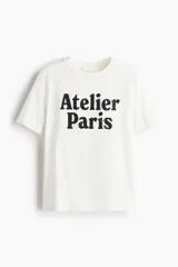 Remera blanca de corte holgado en punto de algodón con estampado negro con la frase "Atelier Paris".