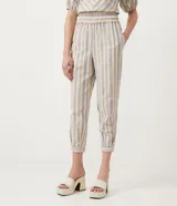 Conjunto de pantalón y blusa de algodón a rayas verticales en tonos beige, celeste y blanco. El pantalón es de corte recto con cintura elástica y puños ajustados. La blusa es de corte crop con escote en V y mangas cortas abullonadas.