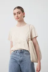 Remera blanca de manga corta con cuello redondo y bordado floral en relieve de color beige claro en el frente.