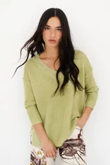 Sweater de tejido de punto fino con brillo metálico, color verde lima. Presenta escote en V y mangas largas.