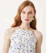 Musculosa blanca con estampado de peces azules, cuello halter con detalle de cuerda y sisa americana.