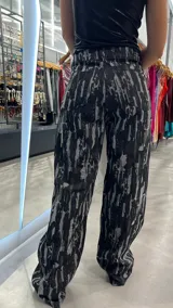 Pantalón de jean negro con estampado abstracto en gris, corte wide leg y tiro alto.