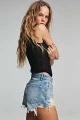 Short de jean de tiro alto, color celeste claro desgastado, con roturas grandes y deshilachado en el bajo. Presenta cinco bolsillos y cierre frontal con botón metálico.