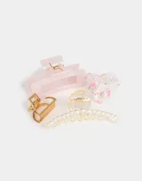 Set de cuatro broches para el pelo de diferentes formas y colores: uno transparente con estampado de flores rosas, uno dorado, uno transparente con perlas y uno rosa.